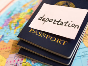 Deportation on a post it placed on a passport on top of a map. 